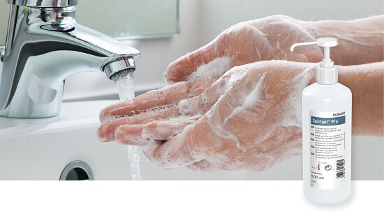 Hands being washed under running water from a faucet with soap lather, alongside a bottle of Ecolab Spirigel Pro hand sanitizer.